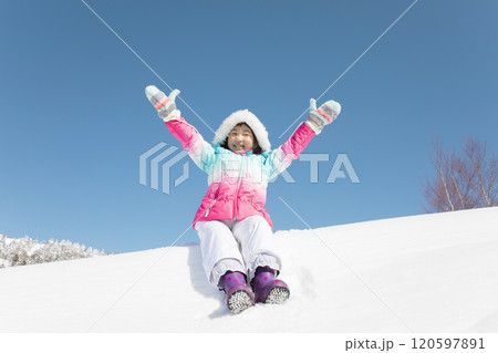 スキー場で雪の上に座って万歳をする女の子 スキー場で雪の上に座って万歳をする女の子 120597891