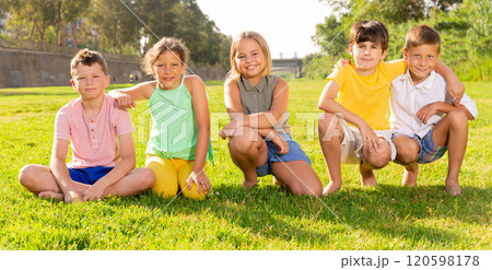 Joyful preteen boys and girls posing on green grass in city park 120598178