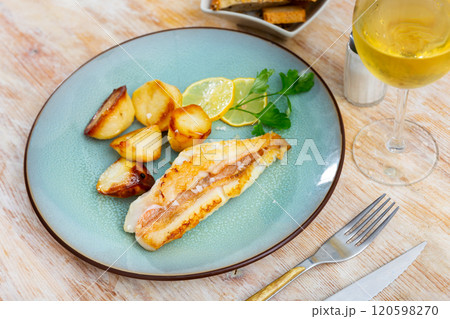On plate, slice of fried redfish garnished with French fries 120598270