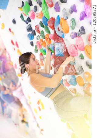 Young woman practicing rock climbing on climbing wall 120598271