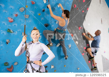 Portrait of sports woman in climbing equipment and safety rope on background of climbing wall 120598325