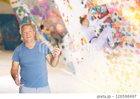 Portrait of positive elderly male coach against background of climbing wall Portrait of positive elderly male coach against background of climbing wall 120598497