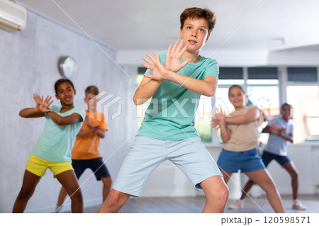 Boy perform choreographic exercises and teach energetic social dance waacking with friends 120598571