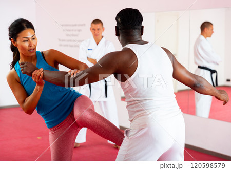 Men and woman training self-protection martial arts in gym 120598579