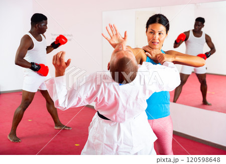 Woman exercising self defence moves with trainer, man boxing in gym 120598648
