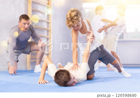 Diligent preteen student twisting his opponent's arm on the floor Diligent preteen student twisting his opponent's arm on the floor 120598680