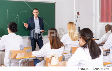 Professor explaining function graph to adult students in auditorium Professor explaining function graph to adult students in auditorium 120598766