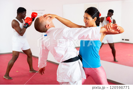Sporty woman with a trainer conducts painful reception on the eyes in gym Sporty woman with a trainer conducts painful reception on the eyes in gym 120598771