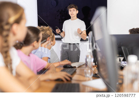 Guy teacher teaches group of students in computer class Guy teacher teaches group of students in computer class 120598777