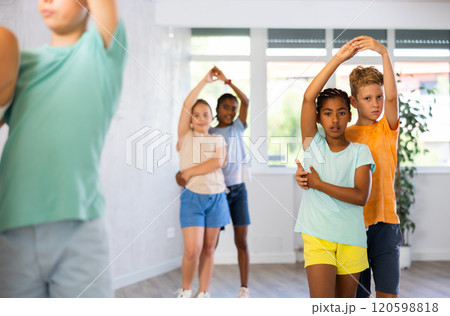 Light-skinned boy and African girlie learn figures of pair jive dance and train before competition 120598818