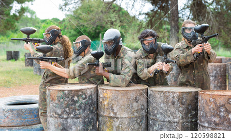 Group of people in full gear playing paintball on shooting range outdoor Group of people in full gear playing paintball on shooting range outdoor 120598821