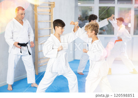 Diligent preteen attendee of karate classes fighting with his opponent in sports hall Diligent preteen attendee of karate classes fighting with his opponent in sports hall 120598851