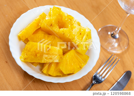 On table there is plate with summer dessert - pieces of pineapple pulp. On table there is plate with summer dessert - pieces of pineapple pulp. 120598868