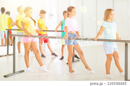 Preteen girls practicing ballet positions near bar in choreographic school 120598885