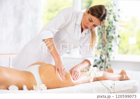 Adult woman masseuse doing thigh and butt massage Adult woman masseuse doing thigh and butt massage 120599073