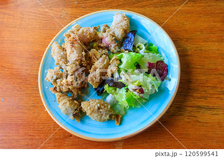 Crispy deep fried baby octopus served with salad on wooden table. Top view 120599541