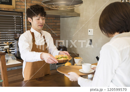 オーダーを受けた食べ物をホールスタッフに渡す店主 120599570