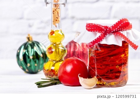 Sundried tomatoes with herbs in a jar for Christmas on a table with ingredients. 120599731