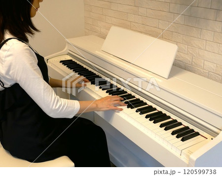 部屋で電子ピアノを弾く女性 120599738