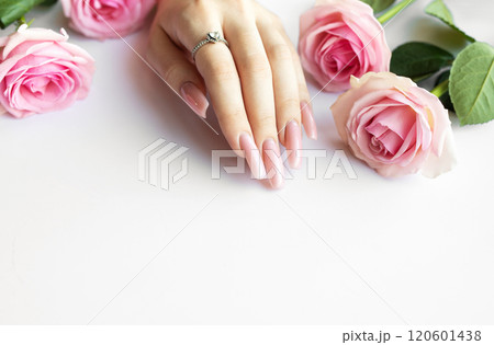 Woman showing long polished fingernails near pink roses Woman showing long polished fingernails near pink roses 120601438