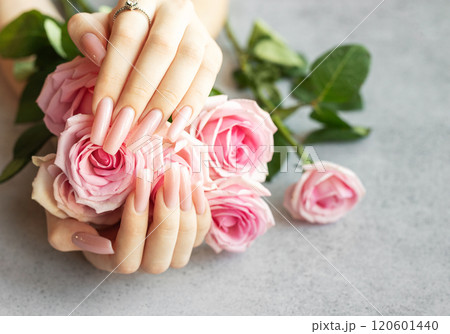 Woman showing pink manicure and diamond ring holding bouquet of roses 120601440