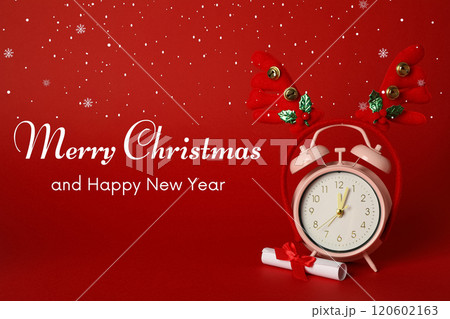 Merry Christmas and New Year, pink alarm clock and decorative deer antlers on a red background with text 120602163