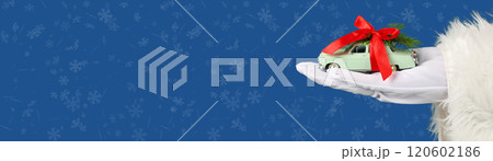 Merry Christmas and happy New Year, car figurine in a hand in a white glove on a blue background with space for text Merry Christmas and happy New Year, car figurine in a hand in a white glove on a blue background with space for text 120602186