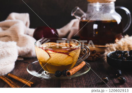 Aromatic tea with apple petals, rose hips and cinnamon in a cup on the table 120602913