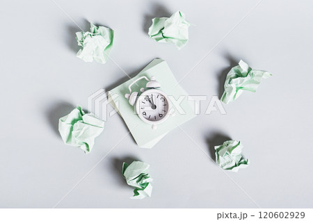 Burnout breaks concept. Alarm clock among crumpled papers on a desk top view 120602929