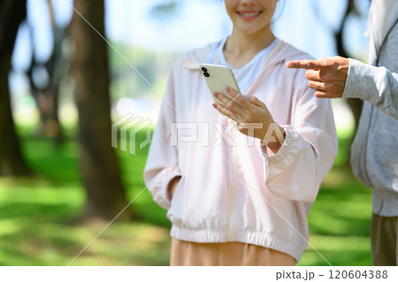Cropped shot of smiling young woman checking smartphone while resting after workout in a park Cropped shot of smiling young woman checking smartphone while resting after workout in a park 120604388