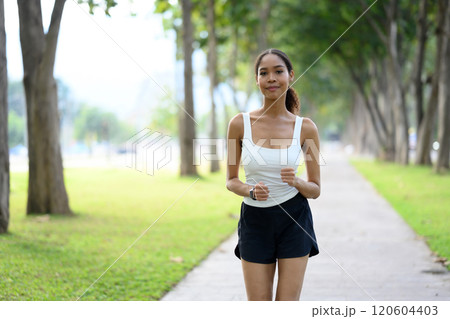 Shot of athletic young woman jogging along a paved pathway in a sunny summer park 120604403