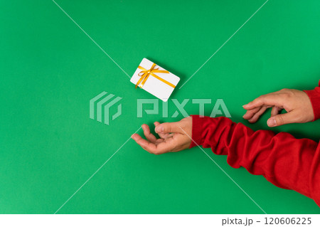 Woman hands holding a white plastic card tied with a yellow ribbon on a bright green background. Suitable for gifting on Christmas, Mother's Day, or special occasions Woman hands holding a white plastic card tied with a yellow ribbon on a bright green background. Suitable for gifting on Christmas, Mother's Day, or special occasions 120606225
