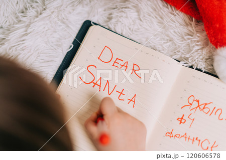 Close up hands of Kid boy, lying on couch and writing letter in note pad to dear Santa at home in Christmas holidays. Child wish list. Dreams of a Christmas gifts. Merry Christmas and Happy new year. Close up hands of Kid boy, lying on couch and writing letter in note pad to dear Santa at home in Christmas holidays. Child wish list. Dreams of a Christmas gifts. Merry Christmas and Happy new year. 120606578