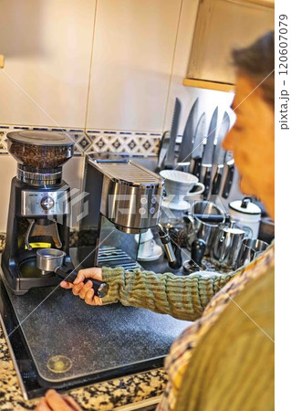 A woman is making coffee in a kitchen with a coffee maker and a grinder A woman is making coffee in a kitchen with a coffee maker and a grinder 120607079