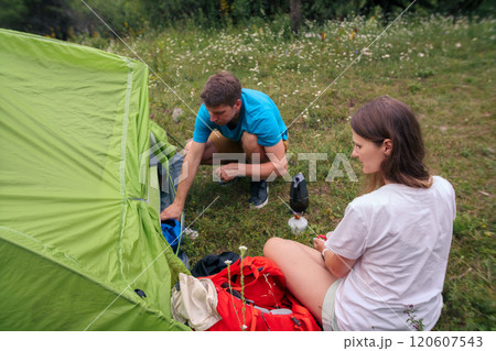 A couple eagerly organizing camping gear in a vibrant outdoor setting, ready for their next adventure A couple eagerly organizing camping gear in a vibrant outdoor setting, ready for their next adventure 120607543