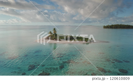 Aerial view of small desert island with palm trees and turquoise coral reef lagoon, Tikehau atoll in French Polynesia. Remote wild nature paradise, summer travel background. Exotic vacation getaway 120610809