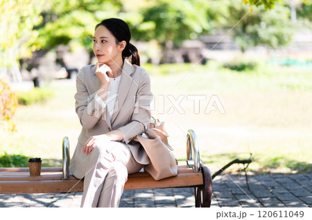 公園のベンチで考えるスーツ姿のビジネスウーマン 120611049