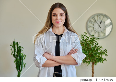 Confident young woman with crossed arms in home interior 120612039