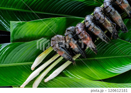 A vibrant display of tiger shrimp rests on lush banana leaves, highlighting a traditional Asian culinary practice. The scene captures the essence of fresh, natural ingredients and culinary artistry. A vibrant display of tiger shrimp rests on lush banana leaves, highlighting a traditional Asian culinary practice. The scene captures the essence of fresh, natural ingredients and culinary artistry. 120612181