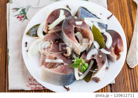 salted mackerel with onions and spices, in a plate on a wooden table salted mackerel with onions and spices, in a plate on a wooden table 120612711