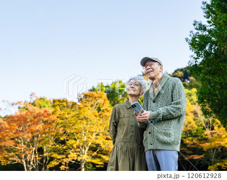 公園でスマホを見ながら空を見上げるシニアカップル 120612928