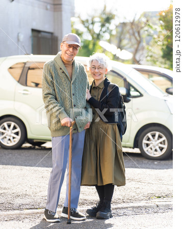 寄り添って駐車場に立つシニアカップル 120612978