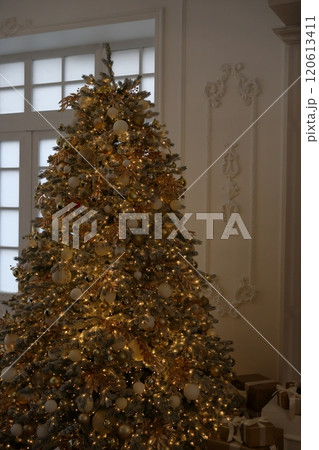 large Christmas tree with garland and toys. New Year's decor, gift box on Christmas Eve large Christmas tree with garland and toys. New Year's decor, gift box on Christmas Eve 120613411