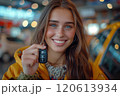 Caucasian woman showing car keys in hand sitting inside car in showroom. 120613934