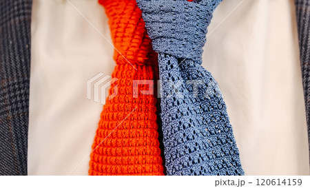 Close-up of vibrant red and blue knitted ties paired with a plaid suit jacket 120614159