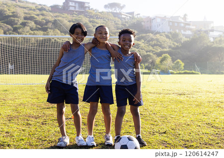 Outdoors, Playing soccer, three multiracial boys in sportswear smiling on school field 120614247
