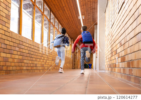 Running down school hallway, multiracial boy and girl with backpacks heading to classroom 120614277