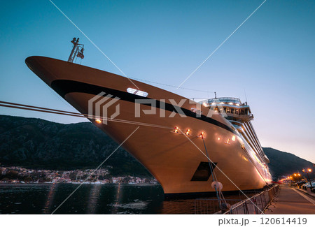 An elegant cruise liner docked at twilight, its lights shimmering against the evening sky, embodying the allure of ocean voyages. 120614419