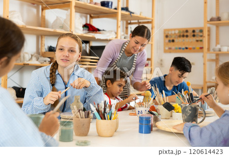 Children painting ceramics with a teacher Children painting ceramics with a teacher 120614423