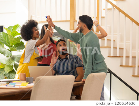 High-fiving, group of young friends celebrating success at home office desk High-fiving, group of young friends celebrating success at home office desk 120614630